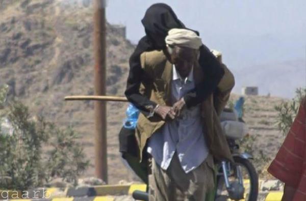 عجوز يحمل زوجته على ظهره هربًا من حصار الحوثيين