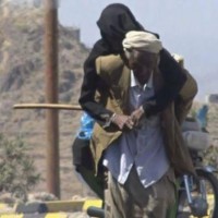 عجوز يحمل زوجته على ظهره هربًا من حصار الحوثيين